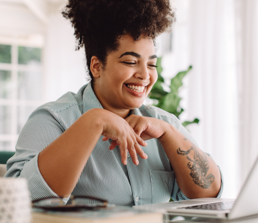 A woman with an afro sits at a desk with a laptop, ready to chat about diversity and inclusion.