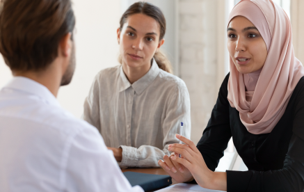 A woman in hijab engaging in conversation with two individuals.