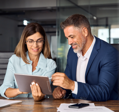 A man and woman in business attire focused on a tablet, discussing important information.